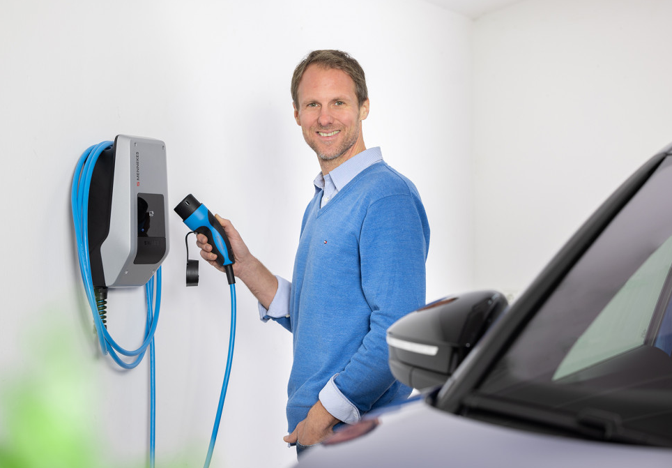 Iemand staat naast een AMTRON® laadpaal